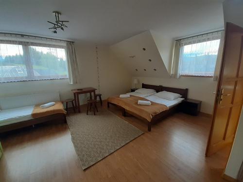 a bedroom with two beds and a table in it at Domek HAWRAŃ in Jurgów