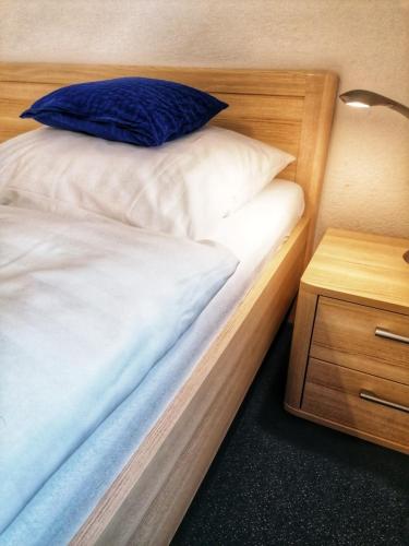 a bed with a blue pillow on it next to a night stand at Das Gästehaus Eimeldingen in Eimeldingen
