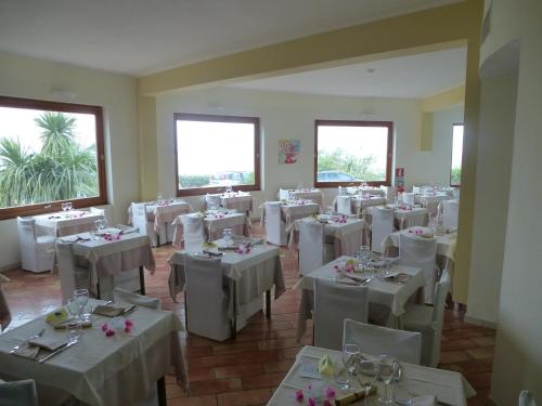 a dining room with white tables and white chairs at LH Pedraladda Resort in Castelsardo