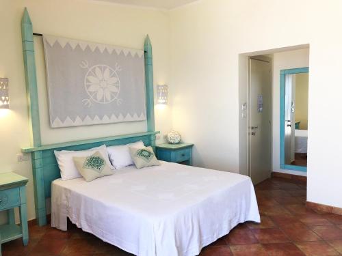 a bedroom with a white bed with two blue tables at LH Pedraladda Resort in Castelsardo