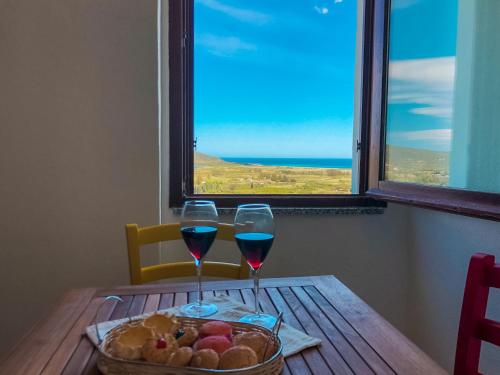 a table with two glasses of wine and a basket of fruit at panoramic LOFT Fora e ' Muros with sea view common terrace , Ammentos Posada in Posada
