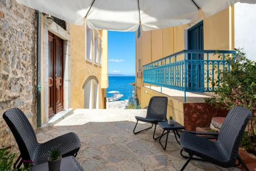 a patio with chairs and a balcony with the ocean at Marika's Deluxe Rooms in Symi