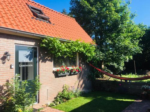 a house with a red roof and flowers in a yard at B&B Larenstein logeren in een tiny house in Velp