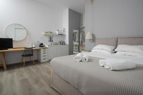 a white bedroom with a bed with towels on it at Syros Wellness Luxury Suites in Finikas