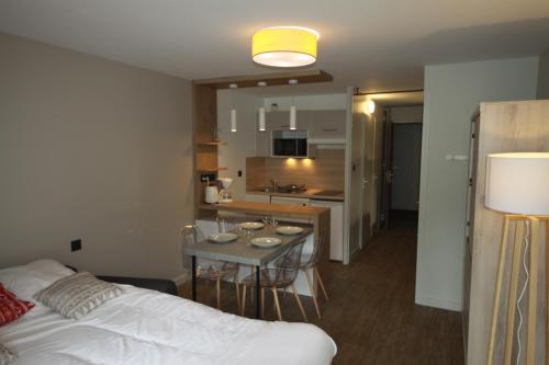 une chambre avec un lit et une cuisine avec une table dans l'établissement Archipel Accueil International - Studio Bois des Coqs, à Saint-Chaffrey