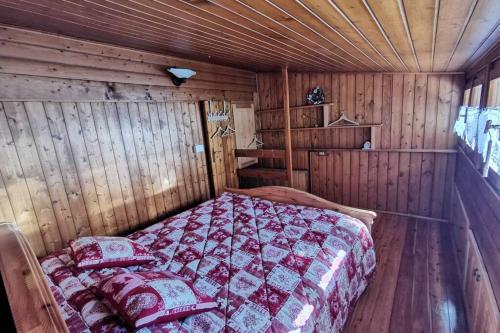 ein Schlafzimmer mit einem Bett in einer Holzhütte in der Unterkunft Casa Bel Vedere in Falcade
