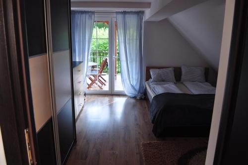 a bedroom with a bed and a sliding glass door at Apartament Stara Leśniczówka in Polnica