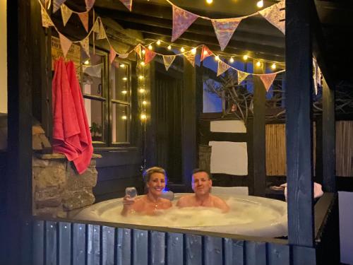 Ein Mann und eine Frau sitzen in einer Badewanne in der Unterkunft The Old Farm in Gloucester