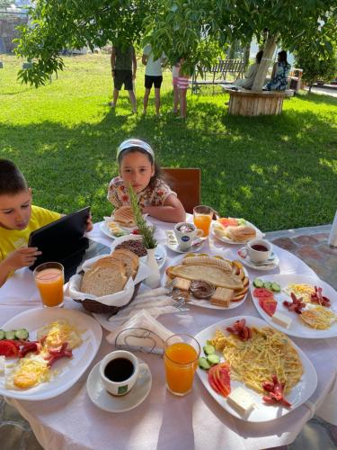zwei Kinder sitzen an einem Tisch mit Frühstücksspeisen in der Unterkunft Ksamil Central Park Hotel in Ksamil