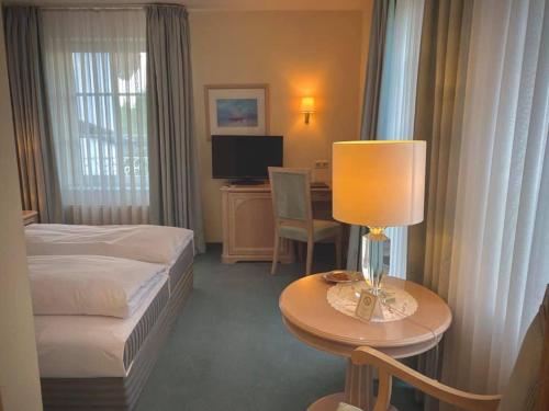 una camera d'albergo con letto e tavolo con lampada di Hotel Daniels a Hallbergmoos