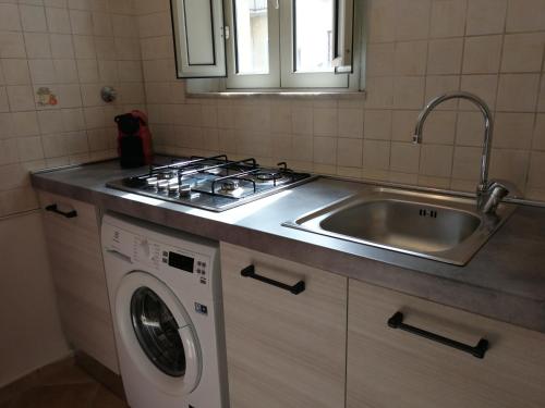 una cucina con lavandino, piano cottura e lavatrice di CASA 739 a Catania