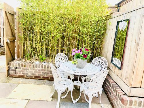 a table with chairs and a vase of flowers on a patio at Amber Lodge Hickstead-C in Haywards Heath