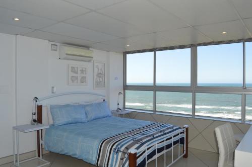 a bedroom with a bed and some windows at Accommodation Front - Classy 4 Sleeper with Ocean Views in Durban