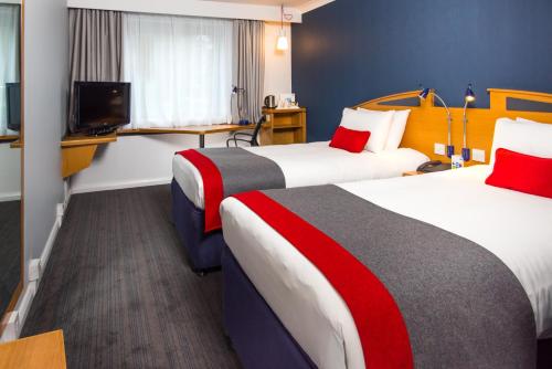 a hotel room with two beds and a television at Holiday Inn Express East Midlands Airport by IHG in Castle Donington