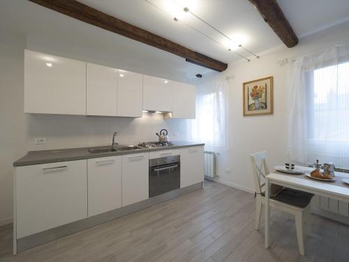 a kitchen with white cabinets and a table and a sink at Residence SS Giovanni e Paolo in Venice