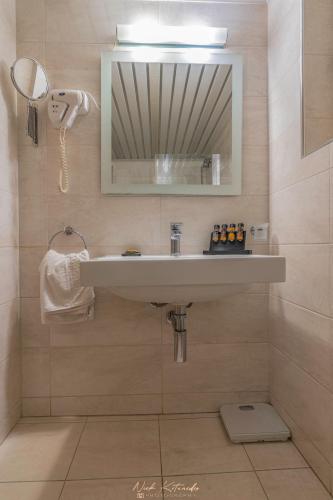 a bathroom with a white sink and a mirror at Hotel Avra in Paralia Katerinis