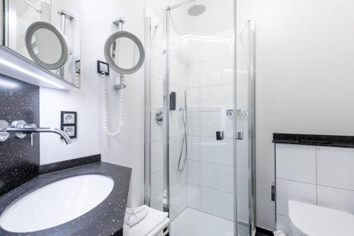 a bathroom with a sink and a shower at Hotel Schloss Wilkinghege in Münster