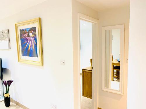a hallway with a mirror and a painting on the wall at Amber Lodge Hickstead-C in Haywards Heath