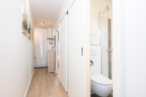 La salle de bains blanche est pourvue d'une douche et de toilettes. dans l'établissement Haus Seeblick Wohnung B7, à Kellenhusen