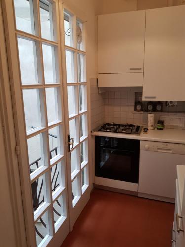 Una cocina con gabinetes blancos y una estufa y una ventana. en Appartamento del Campuccio, en Florencia