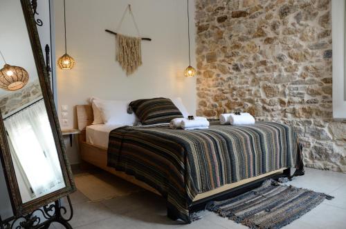 a bedroom with a bed and a stone wall at Deus Apartments_ Athens Airport in Spata