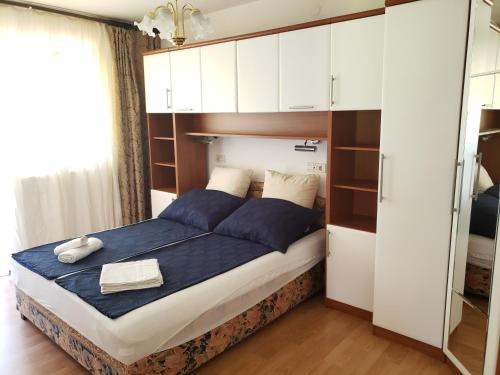 a bedroom with a bed with blue sheets and white cabinets at Risika Apartmani in Risika