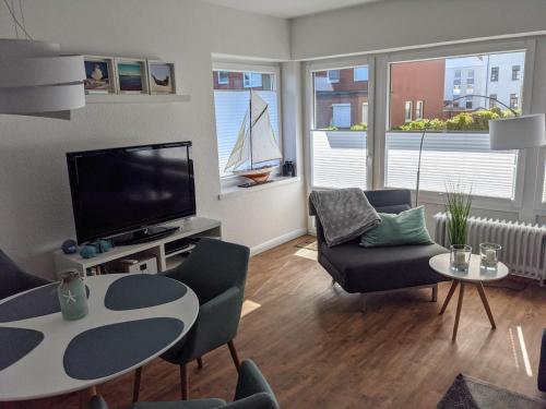 - un salon avec une télévision, une table et des chaises dans l'établissement Panorama, Heimathafen 17 - Ferienwohnung mit Balkon - direkt am Strand, à Wangerooge