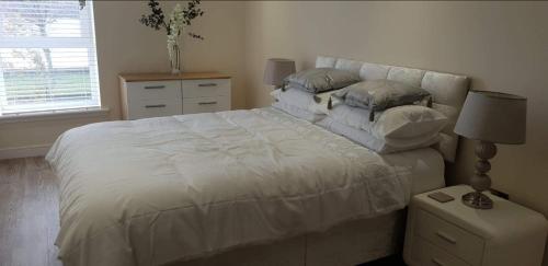 um quarto com uma grande cama branca com almofadas em Waterfront apartment em Dundee
