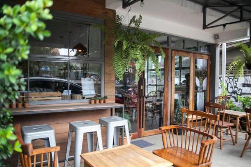 a restaurant with wooden tables and stools in front of it at Oon Poshtel x Cafe in Chiang Mai