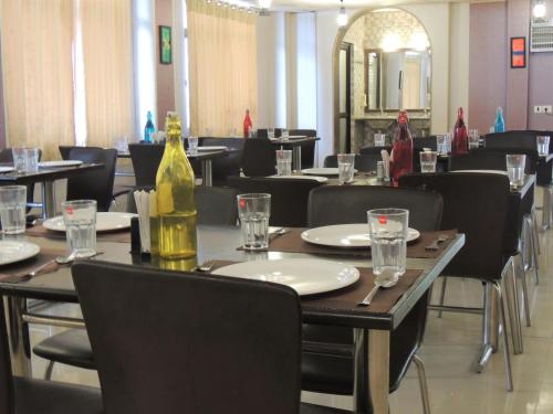 una sala da pranzo con tavoli e sedie e una bottiglia di vino di Ceyone Hotels a Mussoorie