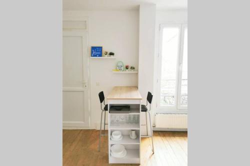 - une cuisine blanche avec un bureau et des chaises dans l'établissement Joli appartement à 2 pas de Paris, à Bagnolet