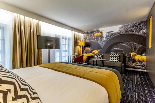 a hotel room with a large bed and a couch at Hotel De Bourbon Grand Hotel Mercure Bourges in Bourges