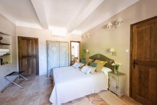 a bedroom with a white bed in a room at Le Mas Silvestre in Saint-Saturnin-dʼApt