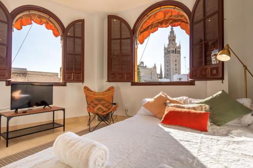 a bedroom with a large bed with windows and a tv at Alianza Giralda Sky view by Valcambre in Seville