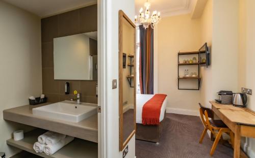 a bathroom with a sink and a table in a room at Kew Gardens Hotel in Kew