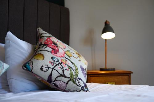 a pillow on a bed with a lamp on a table at Kew Gardens Hotel in Kew