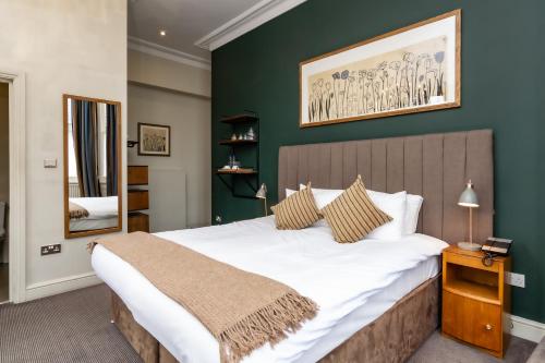 a bedroom with a large bed and a green wall at Kew Gardens Hotel in Kew