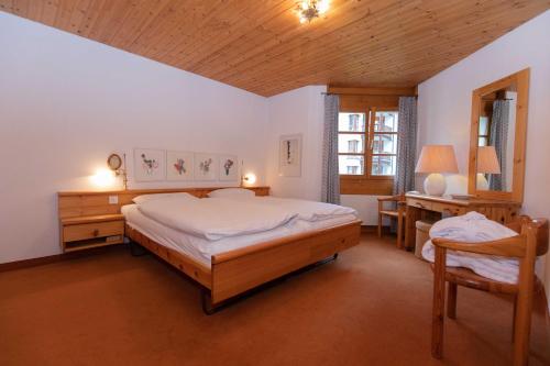 Schlafzimmer mit einem Bett, einem Schreibtisch und einem Stuhl in der Unterkunft Schweizerhof Drescher in Lenzerheide