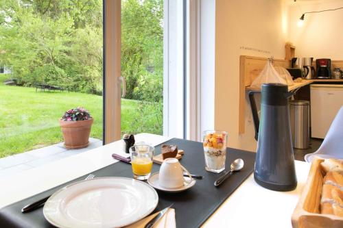 einen Tisch mit einem Teller Essen und einem Fenster in der Unterkunft La Pomme Pétillante in Maisnières