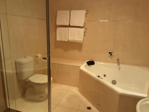 y baño con bañera, aseo y ducha. en Adelphi Apartment 2- Poolside or Apartment 2A- King Studio en Echuca