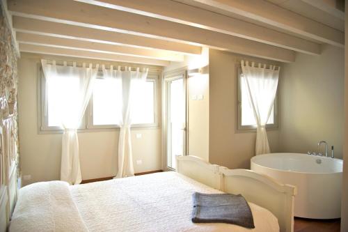 1 dormitorio con cama, bañera y ventanas en Affittacamere Mauro e Sylvie, en Bobbio