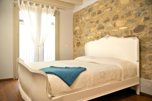 Cama blanca en habitación con pared de piedra en Affittacamere Mauro e Sylvie, en Bobbio