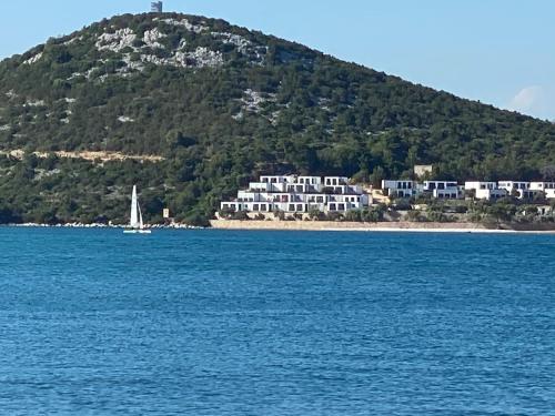 a sailboat in the water in front of a mountain at Bella Homes Camping in Tisno