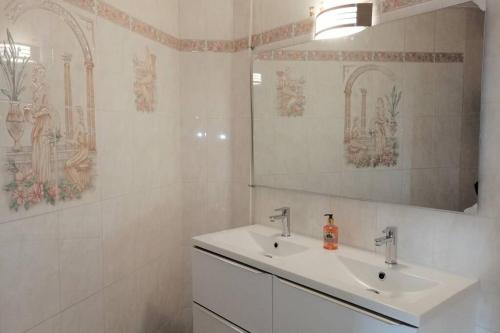 ein weißes Badezimmer mit einem Waschbecken und einem Spiegel in der Unterkunft Confortable 3 pièces très bien placé centre ville in Antibes
