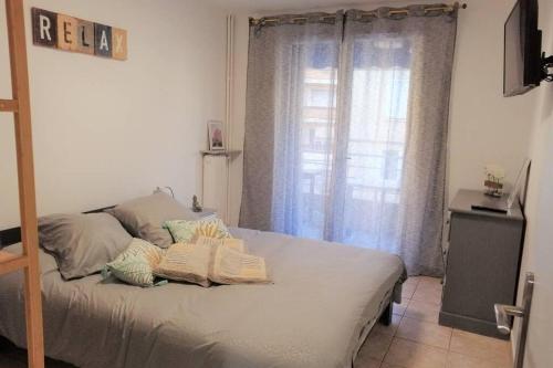 ein Schlafzimmer mit einem Bett mit Kissen und einem Fenster in der Unterkunft Confortable 3 pièces très bien placé centre ville in Antibes