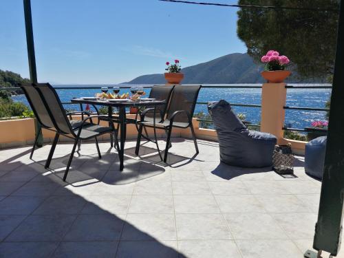 a patio with a table and chairs and a view of the water at Ilios studios in Vasiliki