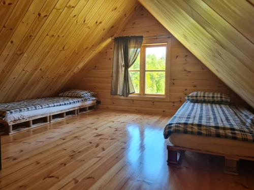 a attic room with two beds and a window at Brīvdienu mājas Lejnieki 