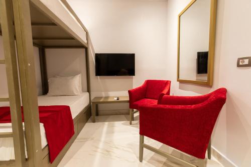 a bedroom with red chairs and a bed and a mirror at Porto Marina Resort & Spa Al Alamein in El Alamein