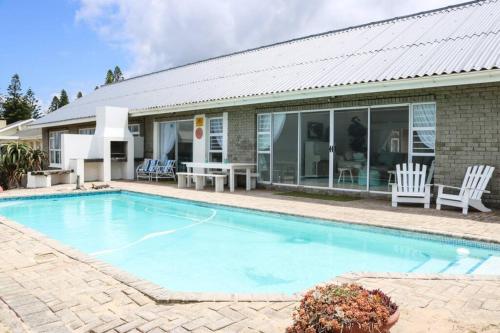 a swimming pool in front of a house at Oceans End - a home on the beach in Kini Bay