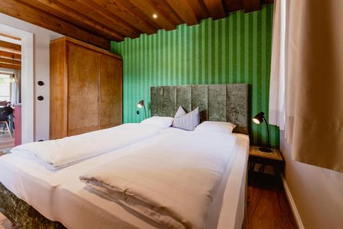 a bedroom with a large white bed with green walls at Zur Nandl in St. Wolfgang